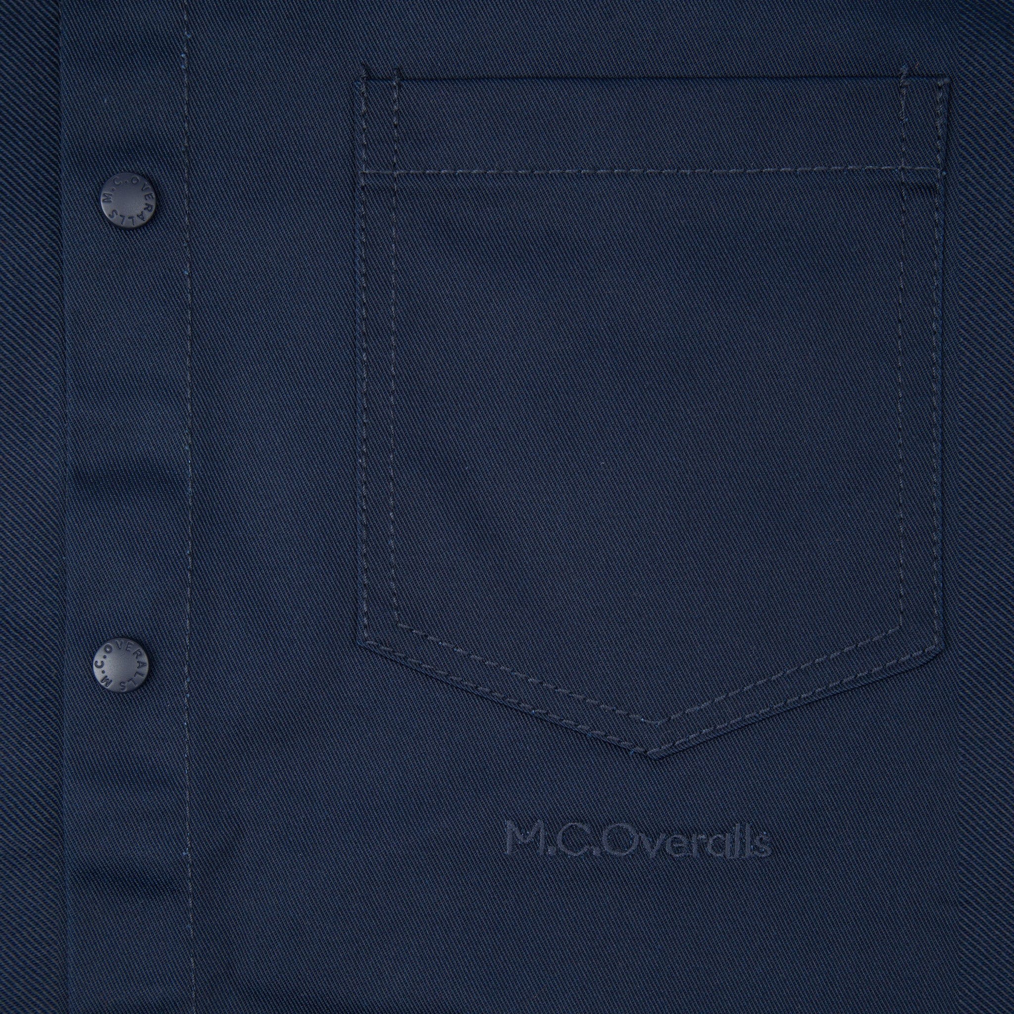 M.C.O's Logo Below the Pocket of the Navy Blue Snap Shirt in Soho, London.