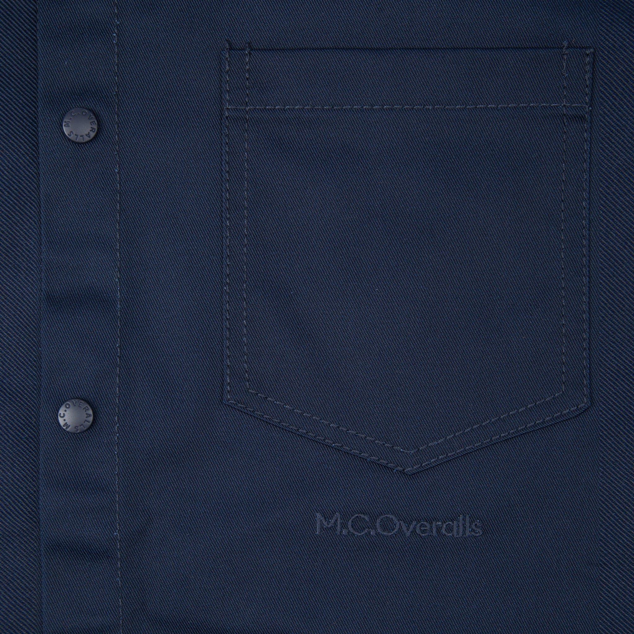 M.C.O&#39;s Logo Below the Pocket of the Navy Blue Snap Shirt in Soho, London.