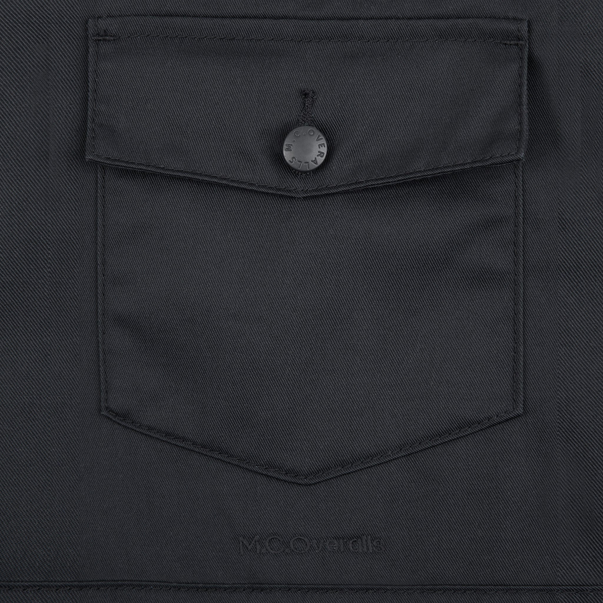 M.C.O's Logo Situated Below the Pocket of Black Polycotton Dungarees.